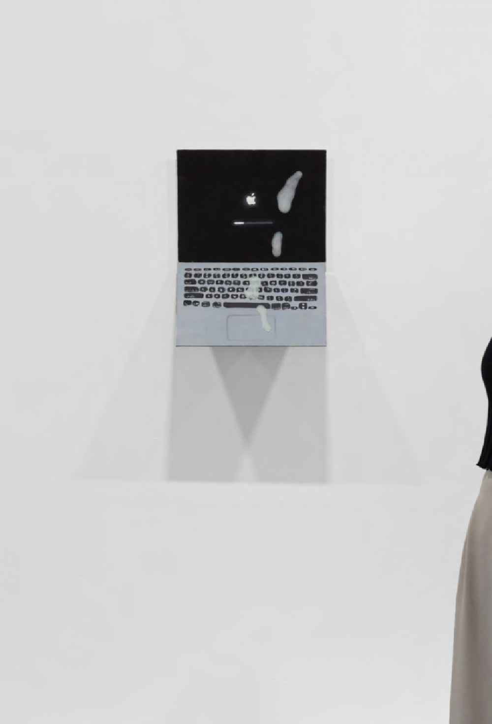 a fake laptop covered in fake cum hanging on a white gallery wall