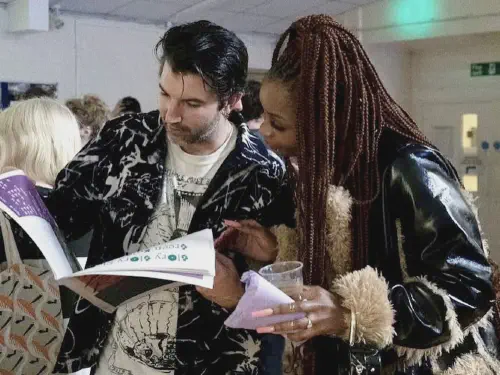 two people reading from the same newspaper at a launch party for the bexley responder