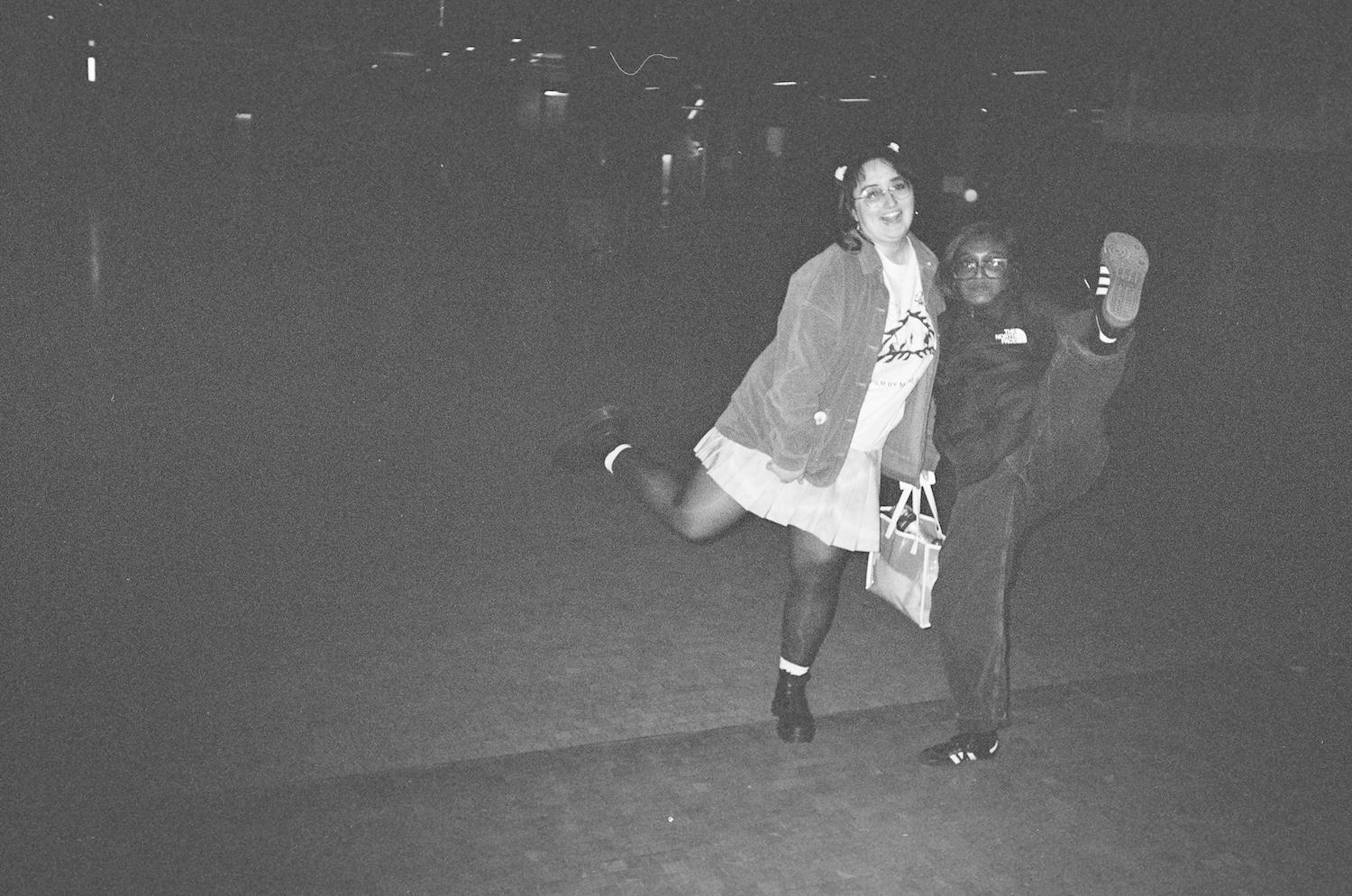 gab and zarina posing with legs up and high kicks in front of saint martins but it's dark so you can't tell really