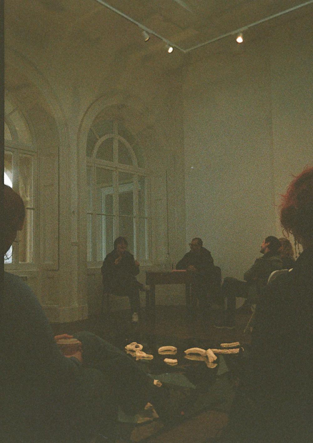 a dark picture with the silhouettes of some people in the distance inside a room