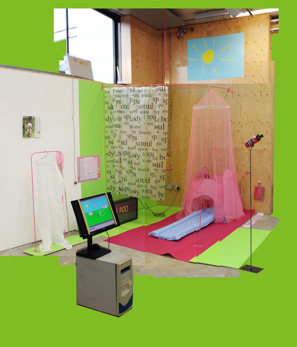 a corner of the studio is painted a green screen green, with a pink rail on the wall holding a shower curtain, and also a pink net that falls down over a kids tent, and in the door to the tend there is a blue lilo. there are more pink rails around it, a rudimentary sun painted in microsoft paint up high on the wall over the scene, and a big metal stand with a tilted top holding an open shower gel for people to smell