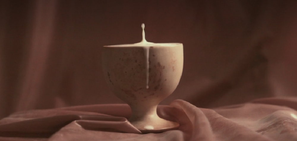 milk dripping out of a hoblet on a pinkish latex table cloth