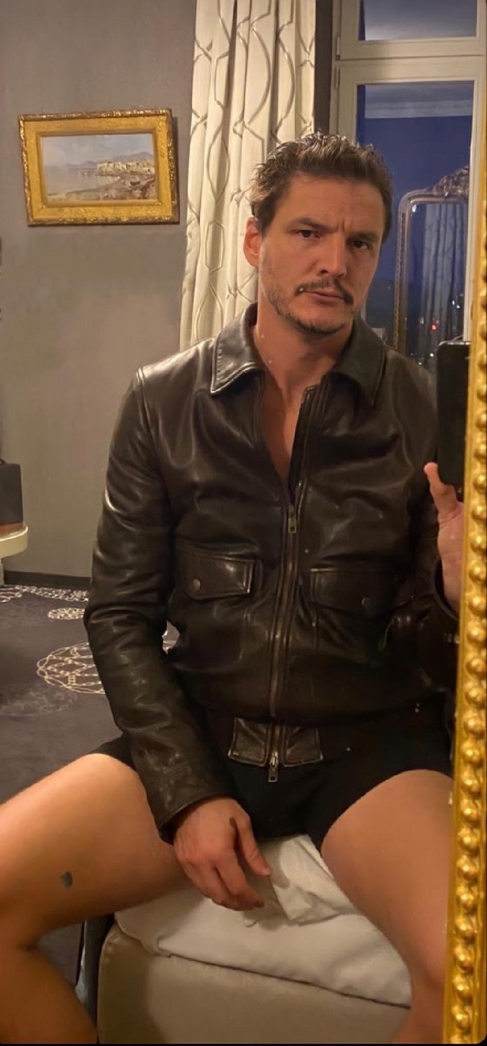 pedro pascal with a leather jacket on but no trousers, on the edge of a bad, its hot