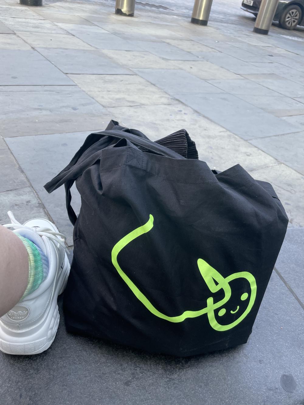 the white pube logo on a black tote bag while i wait for a taxi to take me to a friend's house in london