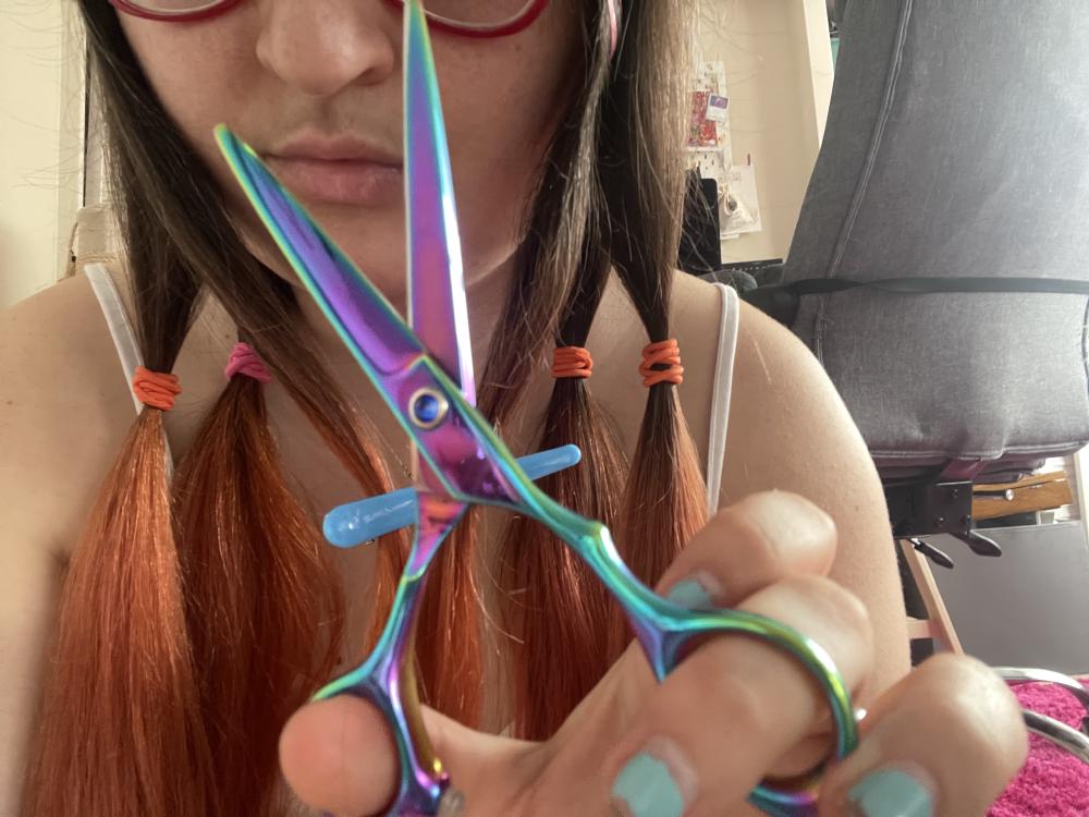gab holds scissors up the camera, behind her hair is sectioned into four with bobbles ready to cut