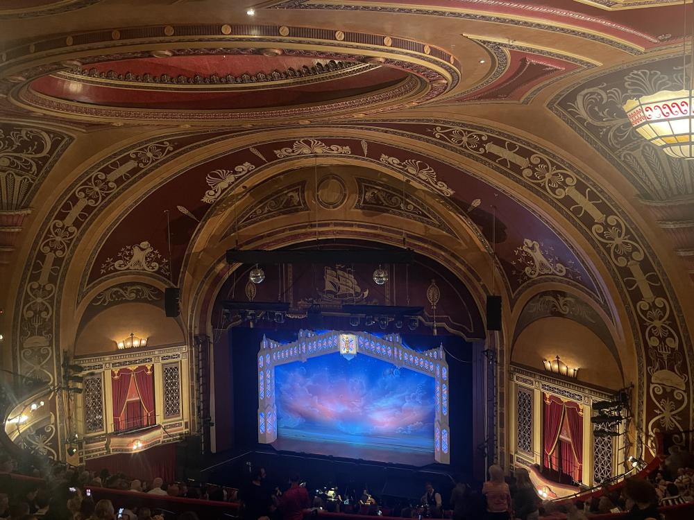 an ornate theatre ceiling at the liverpool empire, with a heavenly blue cloudy image on the stage