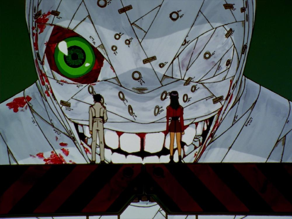 two people on a bridge look up at a huge scary grinning figure which has a bandaged face and one green eye visible
