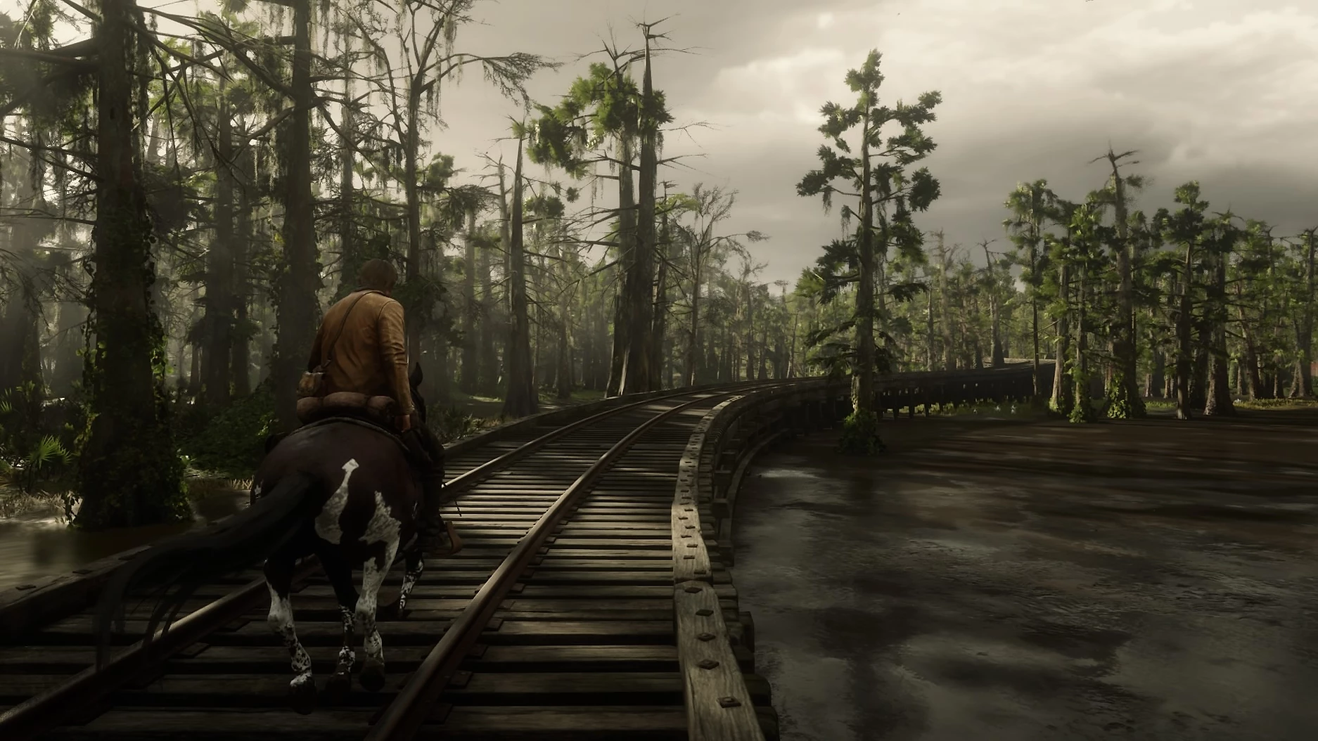Screenshot of Red Dead Redemption 2, man on horse walking down railway