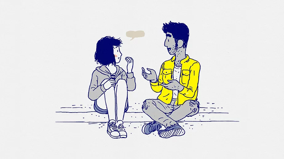 Florence is sat on a curbside speaking to a boy. He is brown, stubble, good hair, and he has a bright yellow jacket on. They look happy together