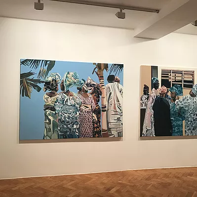 we can see one and a half paintings on a gallery wall, showing groups of people stood around together. Everyone in the paintings is black, and the women are wearing patterned dresses with scarfs around and out from their heads, and in the first image we can see the edges of palm trees too and it looks very bright and social