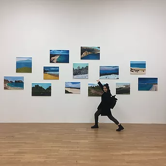 Gabrielle stands below a collection of images of the coast