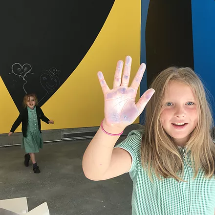 Erin holds her hand up to the camera showing all the chalk she has on her hand