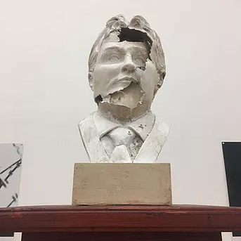 a bust of some white man is cracking across the face to reveal a hollow space inside