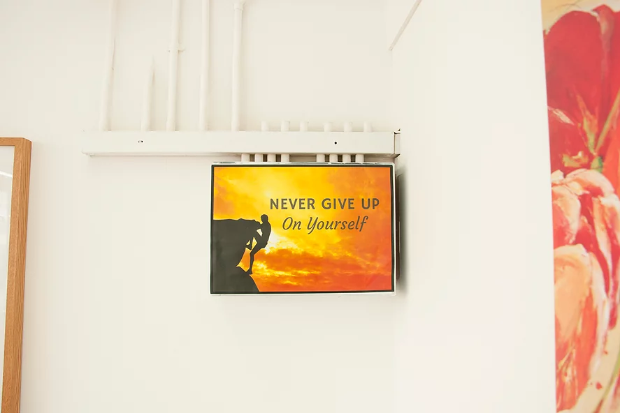 an inspirational picture stuck on the wall that says never give up on yourself