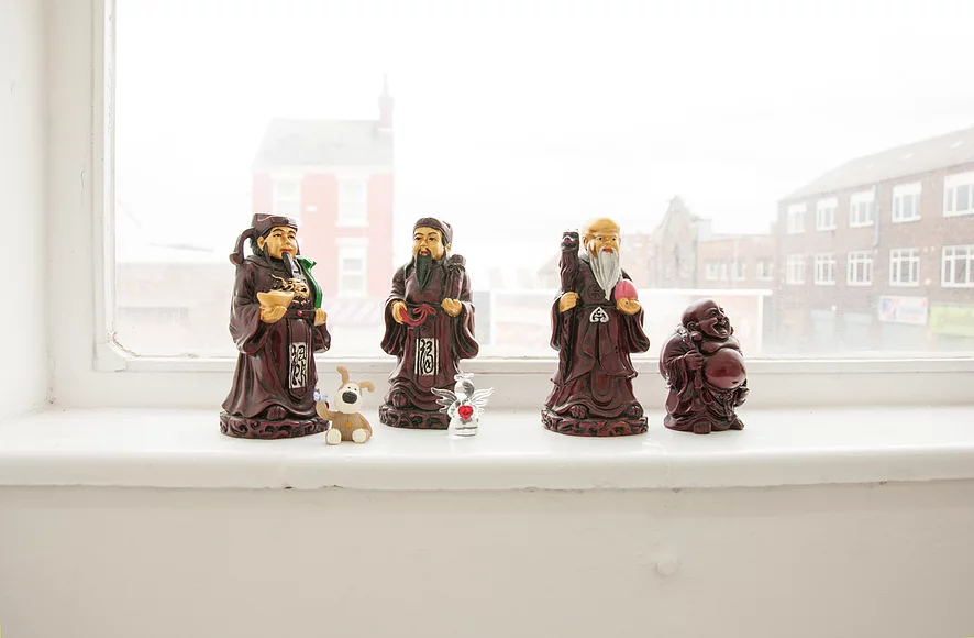 a set of figures of three chinese monks wearing dark brown cloaks