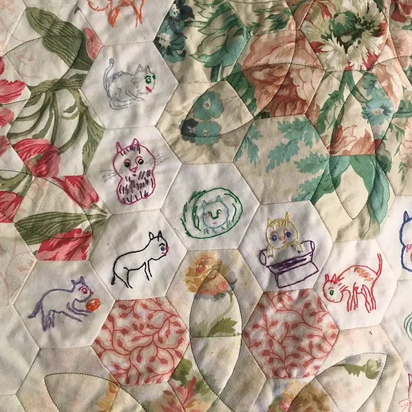 the patchwork quilt also has hexagonal shapes with animals stitched onto them, cats in different poses and colours