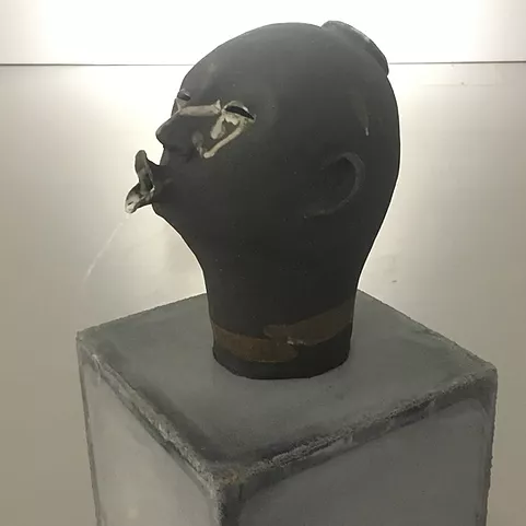 another sculpture of a black head with lips poking out and forward in a dramatic pose, but this one is not connected to water for a fountain, it almost looks like an outtake