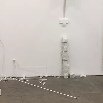 there are white bits of sculpture on the floor, a tower of little blocks, and metal wires in an odd arrangement