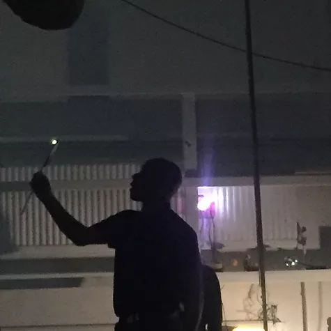 a silhouette of a man holding a stick up that has a light on the end of it