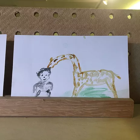 a watercolour of a giraffe bending down to touch a kid on its head
