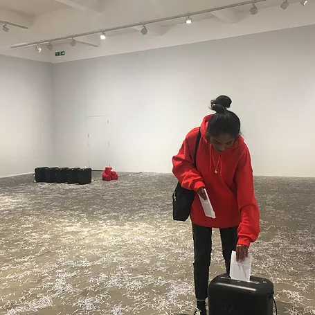 Zarina takes one of the books from the centre of the gallery and pushes it into a shredder