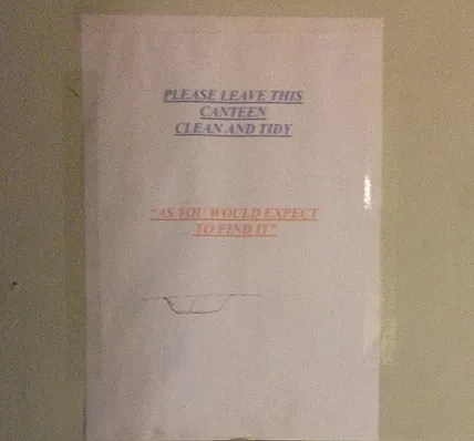 a4 paper cellotaped to the wall that says please leave this canteen clean and tidy as you would expect to find it