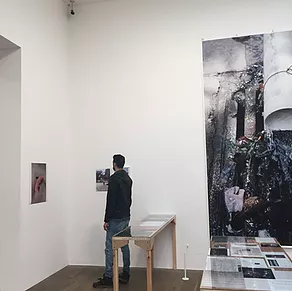 someone stands at the corner of the gallery looking at images on the walls