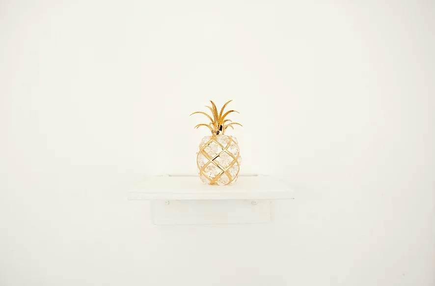 a small crystal pineapple with gold details is sat on a shelf