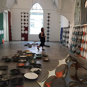 Gabrielle walks through a big gallery room and there are all these big pieces of metal with circles cut out of them, and then in the centre of the room on the floor are tonnes of bowls