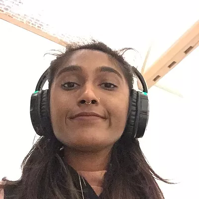 Zarina smiles at the camera with big headphones on
