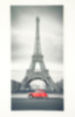 a black and white photo of the eiffel tower with a car below it in bright red