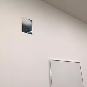 a picture is stuck at the top of a wall, and its hard to see what it depicts, a blurred landscape, a4