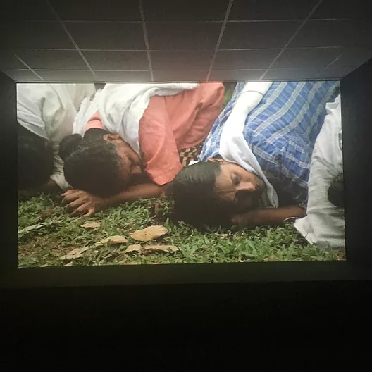 a projection shows people leaning over on the floor as if they are trying to listen to the ground
