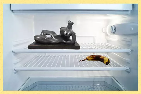 a shot inside a fridge showing a banana on one shelf and a sculpture of a lounging body all abstract on another, nothing else in the fridge but those two