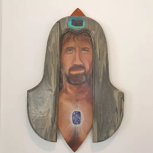 a painting of a white man with a jewel on his chest that is glowin, and stuck on top of the painting there&rsquo;s a wooden piece that drapes down over his face like a hood