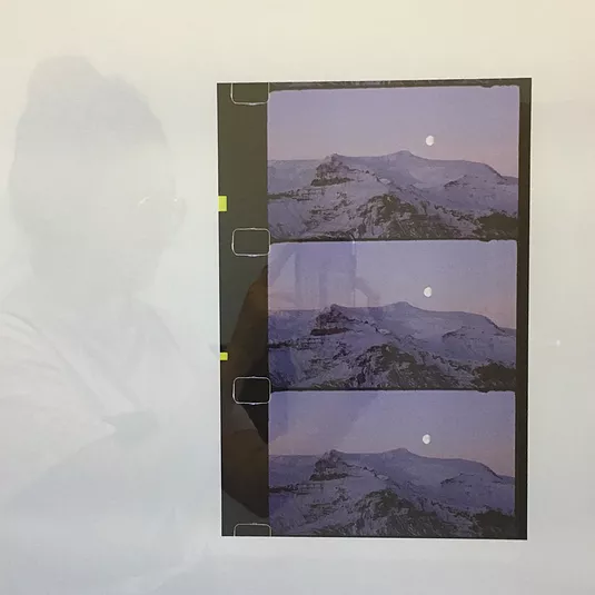 three film images on a wall of a moon above a snowy mountain