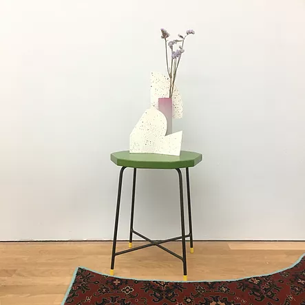 a chair with a vase on it and little purple flowers