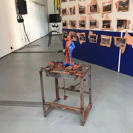 a tiny metal frame table with an orange figure on top of it wearing a suit