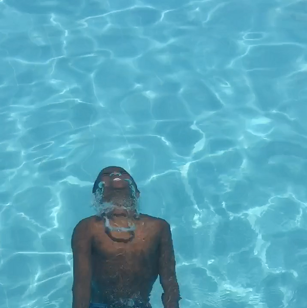 a young black boy is now seen diving up from the water