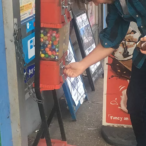 someone leans down to take a bounce ball out of a 20p machine