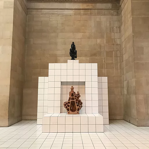 a tiled alter shape on top of tiled floor, and at the centre there is a bubbling pointed sculpture, and another one that has holes through it