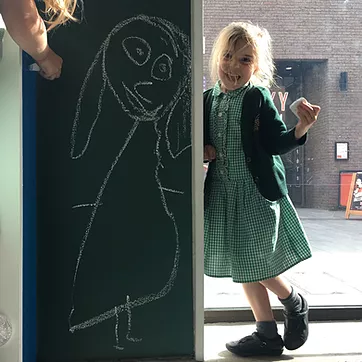 Ivy is stood laughing next to a lifesize drawing of herself in chalk on the wall