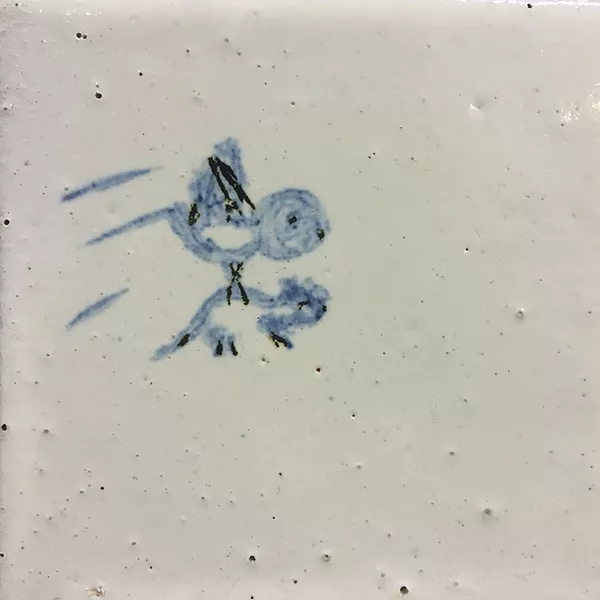 a white tile with a tiny rough bird painted in a light blue, and the bird has something in its feet - it looks like a mouse but they are similar sizes