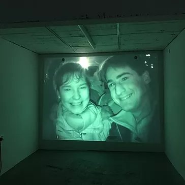 a full wall projection of two people smiling on home video at a new years eve celebration
