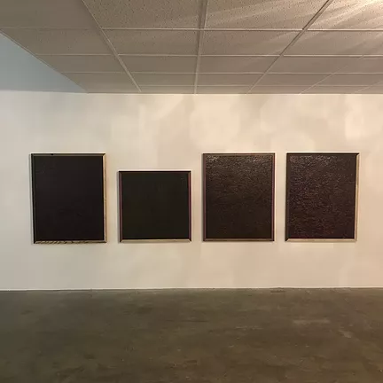 four square framed artworks along a wall, with totally dark centres