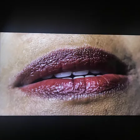 a close up on a black womans mouth with dark red lipstick on