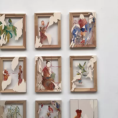 wooden picture frames with empty space inside have pieces of painted paper carefully placed on top in little scenes of figures, plants, and abstract shapes that look like birds and clouds and smoke and mountains
