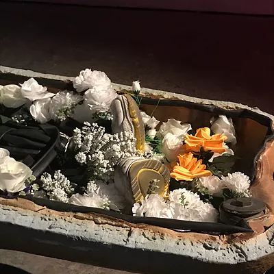 an assortment of fake white flowers, orange roses, in a small clay bath-shaped container