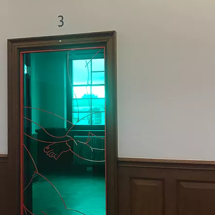 a doorway is blocked by green plastic or glass, and it has a red frame and the thin red outline of arms and legs very minimally