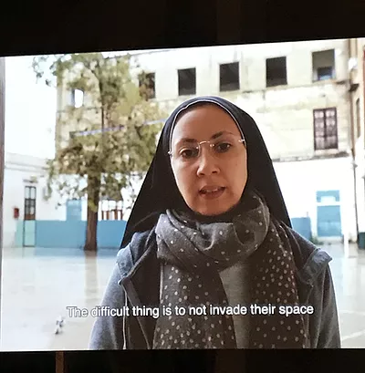 a woman with glasses and a headscarf on a video says &lsquo;the difficult thing is to not invade their space&rsquo;